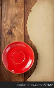 red saucer and old retro aged paper parchment  at wooden background