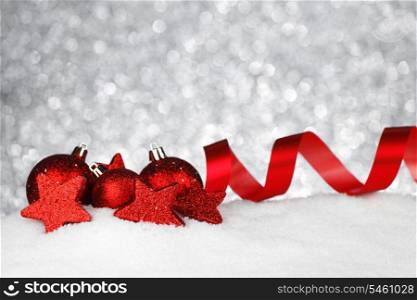 Red shiny Christmas balls and ribbon on snow