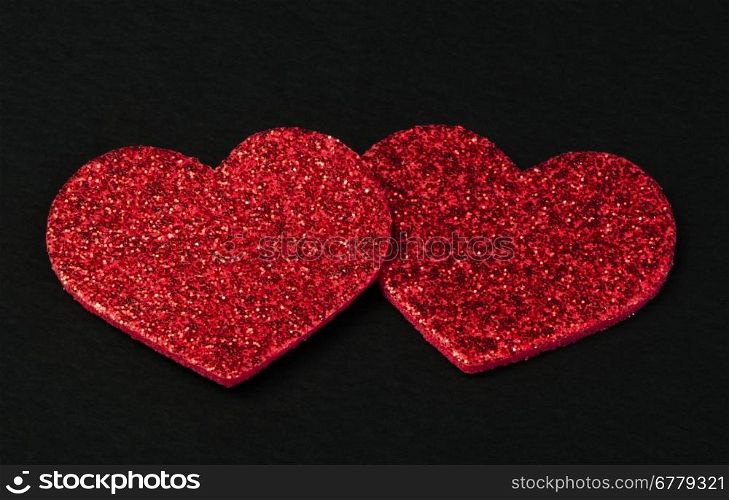 Red shiny hearts on black background. Brocade made hearts