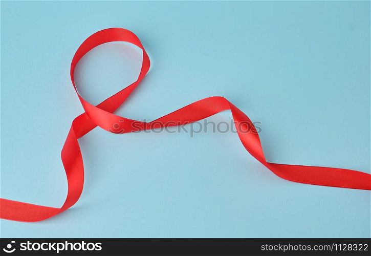 red silk thin ribbon twisted on a blue background, trendy classic color, close up