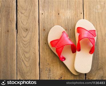Red slippers placed on wooden floor.