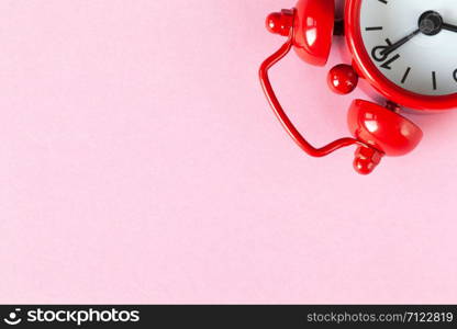 Red small alarm clock on light pastel pink background with copy space, flat lay. Minimal style. Time management concept, free time for important things. One watch is located in upper corner.