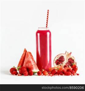 Red smoothie in glass with drinking straw at white background with fruit ingredients  watermelon, pomegranate, strawberries and raspberries. Healthy refreshing drink. Front view.
