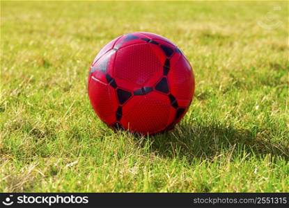 Red soccer ball on green grass field