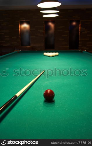 Red sphere on a billiard table in a night club