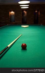 Red sphere on a billiard table in a night club