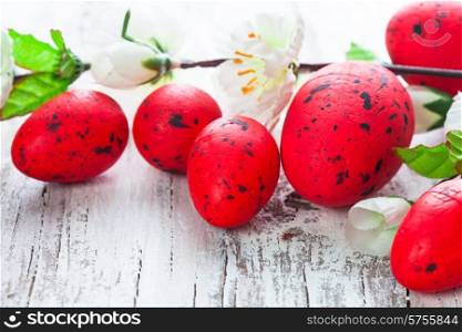 Red spotted eggs with apple flowers on the shabby wooden table. Red eggs