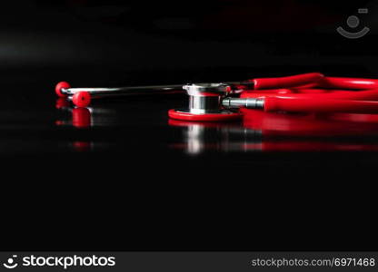 red stethoscope on black background. Healthcare and medicine concept