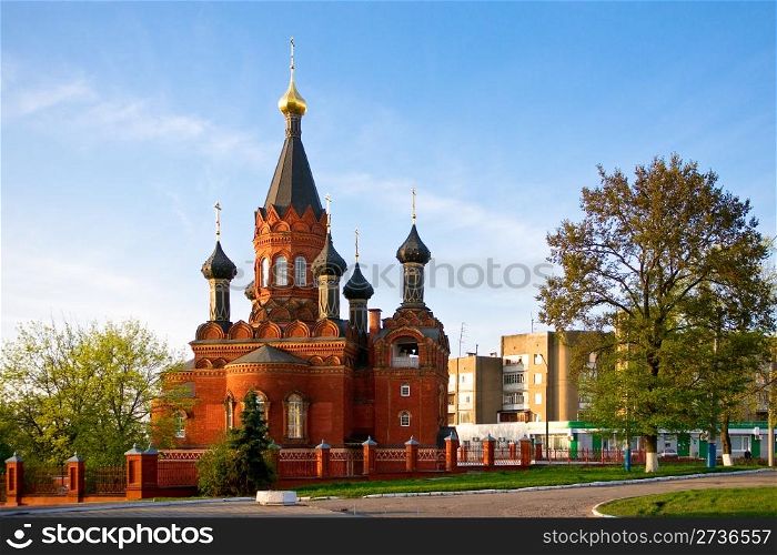 Red stone orthodox church with black cupolas, Bryansk region, Russia