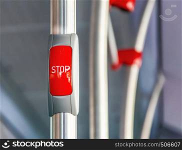 Red stop button on the metal handrail of a bus. Public transport. Public transportation