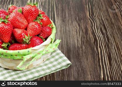 Red strawberry in a basket on brown wooden background with copy space for text. Basket of strawberry