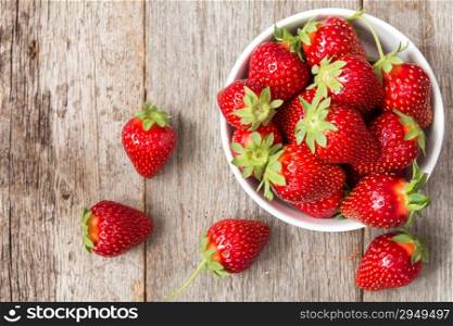 Red strawberry in a bowl on wooden background