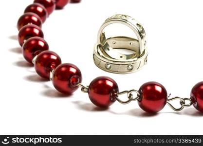 Red string of beads and wedding rings closeup on white background