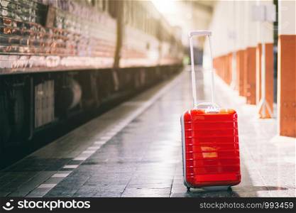 Red suitcase at railway station travel
