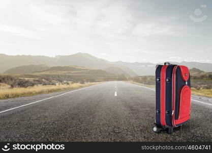 Red suitcase on road. Travel concept with red suitcase on road