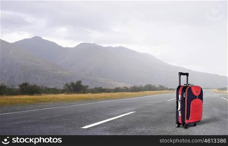 Red suitcase on road. Travel concept with red suitcase on road