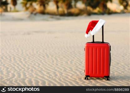 Red suitcase with Santa Claus red hat on handle with tropical sand beach, palms, mountains and sea background. Travel concept for the Christmas holidays and New Year. Place for text. Discounted trips.. Red suitcase with Santa Claus red hat on handle with tropical sand beach, palms, mountains and sea background. Travel concept for the Christmas holidays and New Year. Place for text. Discounted trips