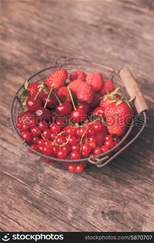 Red summer fruits in metal basket on the table. Red summer fruits