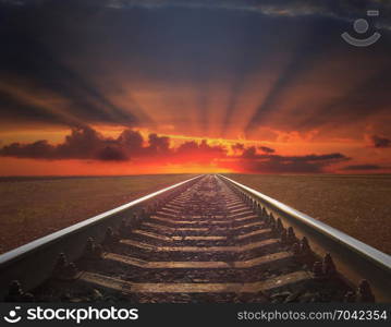 red sunset with rails going away. red sunset with rails going away. rails going away into the dark landscape with fiery red sunset