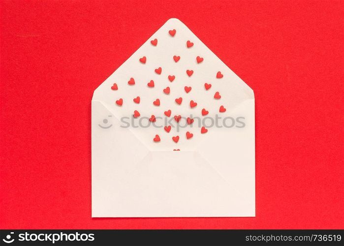 Red Sweets sprinkles candy hearts fly out of white paper envelope, located in the middle on red background. Top view Copy space for text. Concept Valentines day and Valentine card. Gift, message with love.. Red Sweets sprinkles candy hearts fly out of white paper envelope on red background. Top view Copy space for text. Concept Valentines day and Valentine card. Gift, message with love