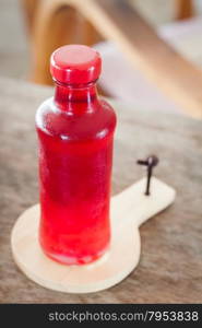 Red syrup in the bottle on wooden plate, stock photo