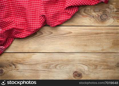 Red tablecloth on wooden background. Top view. Copy space
