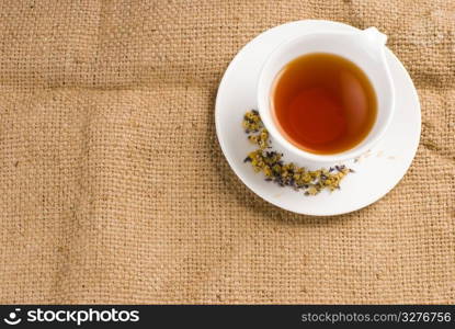 Red tea in white ceramic cup with burlap background