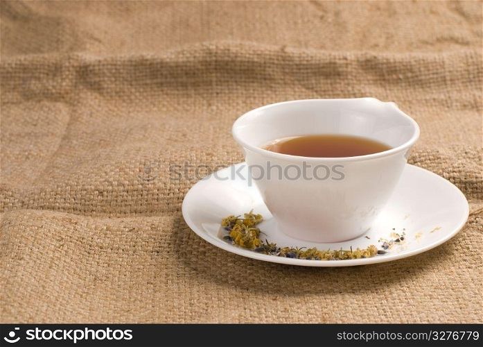 Red tea in white ceramic cup with burlap background