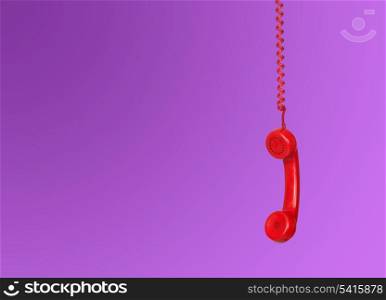 Red telephone cable hanging isolated on purple background