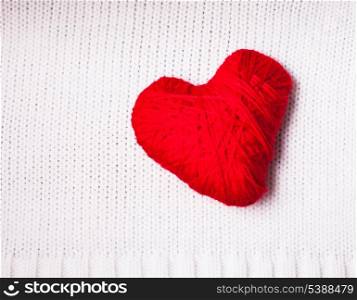 Red thread heart over knitted white textile. Valentine background