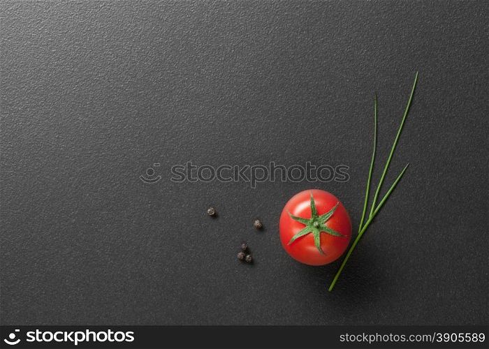 red tomato with green onion on black