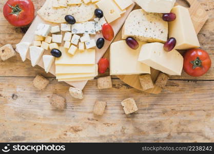 red tomatoes grapes olives cheese blocks wooden desk