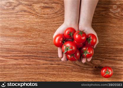 red tomatoes in hands on wooden background