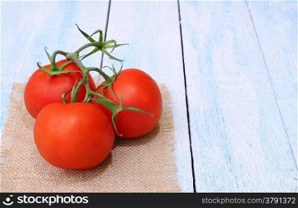 Red tomatoes on a blue kitchen table.