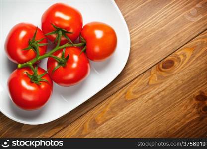 Red tomatoes on wooden table, top view with copy space