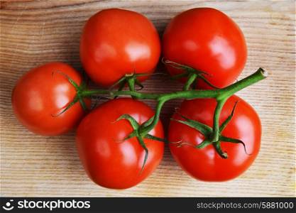red tomatoes with branch on wooden background