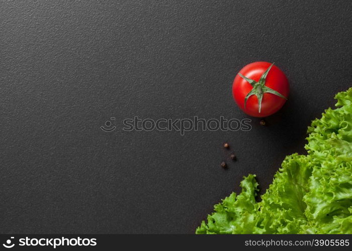 red tomatoes with green salad on black