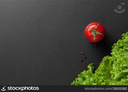 red tomatoes with green salad on black