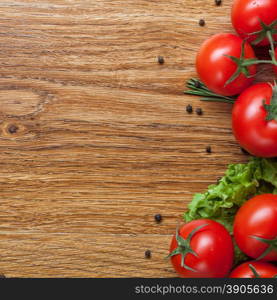 red tomatoes with green salad on wooden background