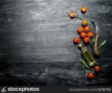 Red tomatoes with rosemary and a bottle of olive oil. On black rustic background.. Red tomatoes with rosemary and a bottle of olive oil.
