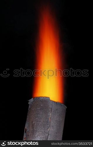 Red torch flame over the old metal chimney at night