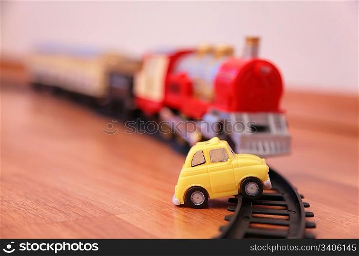Red toy train and yellow toy car on railroad