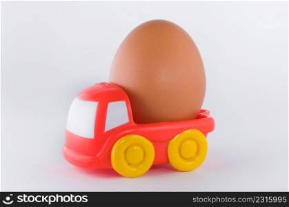 red toy truck loaded with an egg on white background