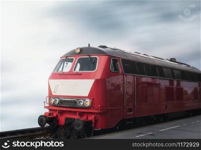 Red train locomotive on rail tracks and railway platform. Train travel concept. Retro train and railway station. German train locomotive.