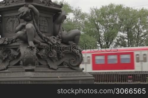 Red train on the bridge passes by in Hamburg, Germany. Column detail.