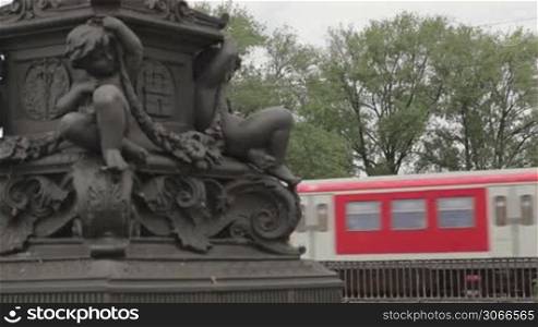 Red train on the bridge passes by in Hamburg, Germany. Column detail.
