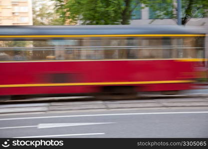 Red tram in Warsaw rushing by at speed on the road