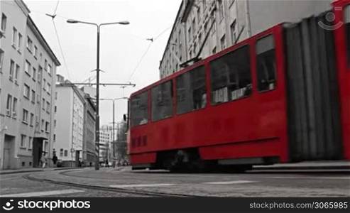Red tram passing the central street of the bw city