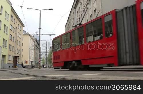 Red tram passing the central street of the city.