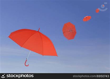 Red umbrella blown by the wind in concept for management business idea on blue sky background.